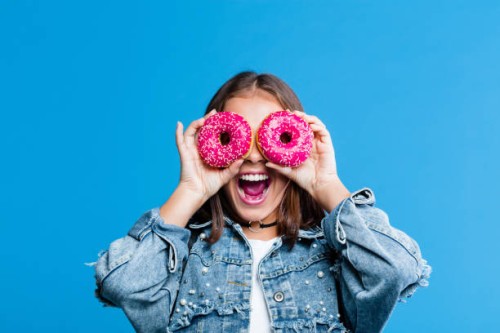 excited teenage girl covering eyes with donuts - food stock pictures, royalty-free photos & images