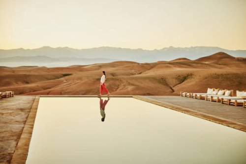 extreme wide shot woman walking poolside at luxury desert camp - travel stock pictures, royalty-free photos & images