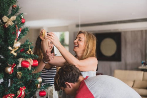 familie decoranting de kerstboom thuis - home decoration stockfoto's en -beelden