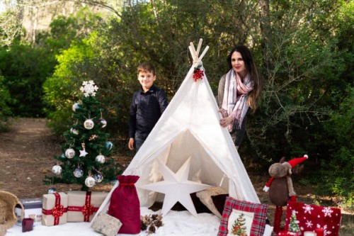 family enjoying christmas decorations next to teepee in the forest - garden decoration stock pictures, royalty-free photos & images