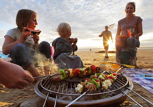 family having bbq on beach at sunset - food stock pictures, royalty-free photos & images