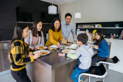 family of four enjoying chinese takeout in modern kitchen - junk food stock pictures, royalty-free photos & images