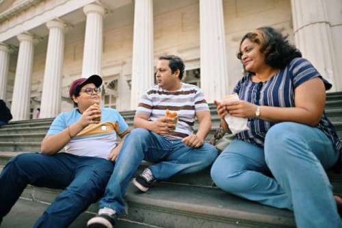 family with a teenage son enjoying street food sitting on the steps - junk food stock pictures, royalty-free photos & images
