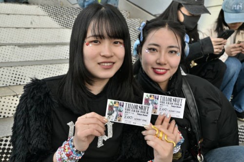 Fans of US singer Taylor Swift, also known as Swifties, pose with their tickets as people gather in front of the Tokyo Dome a few hours ahead of the...