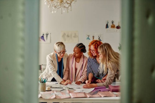 fashion designers in a meeting standing reviewing a sketches - fashion stock pictures, royalty-free photos & images