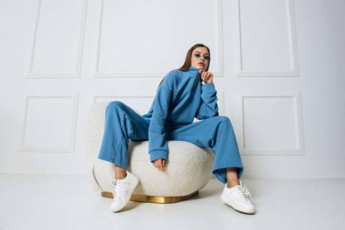 fashion model woman posing sitting on armchair in studio room. pretty lady with glasses indoors - fashion stock-fotos und bilder