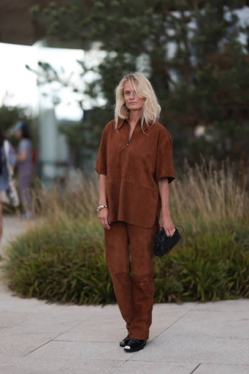 Fashion Week guest is seen wearing a brown suede matching two-piece, consisting of a short-sleeved top with half-zip and collar, and long...