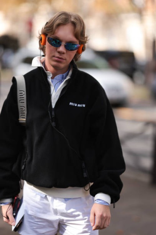 Fashion Week guest is seen wearing a complete outfit from Miu Miu, consisting of rimless oval sunglasses with blue mirrored lenses and silver metal...