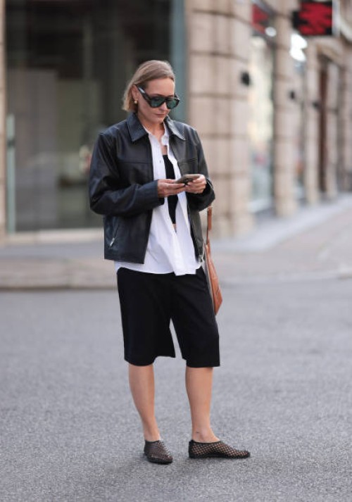 Fashion Week guest is seen wearing havana-framed sunglasses with wide temples and blue lenses from Tom Ford Bronson, golden round earrings, a black...