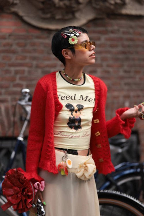 Fashion Week guest is seen wearing several multicolored hair clips, rectangular sunglasses with yellow transparent frame and wide temples from Linda...