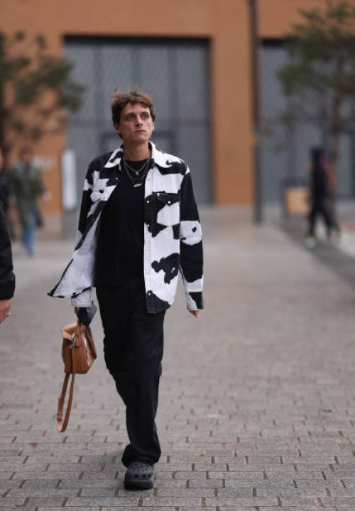 Fashion Week guest is seen wearing several golden necklaces, a jeans jacket with black/white cow print from Calvin Klein Jeans, underneath a black...