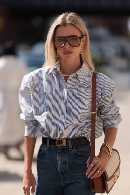 Fashion Week Guest seen wearing a white and darkblue blouse, denim blue jeans, black heels, white and brown Celine handbag, sunglasses and a black...