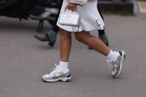 Fashion week guest seen wearing a white dress, a silver bag, white socks and silver and white sneakers before the Chanel show on March 07, 2023 in...