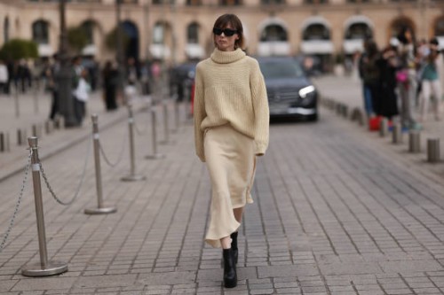 Fashion Week Guest was seen wearing black heels, a beige longsleeve with turtle-neck as well as a matching light beige skirt and dark shades before...