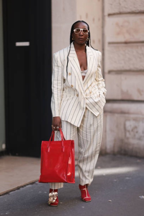 Fashion Week guest was seen wearing red socks and a red bag, yellow gold earrings, beige shades as well as a white bra, yellow gold shoes with...