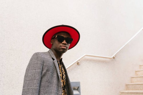 fashionable man wearing hat and sunglasses standing in front of wall - fashion photos et images de collection