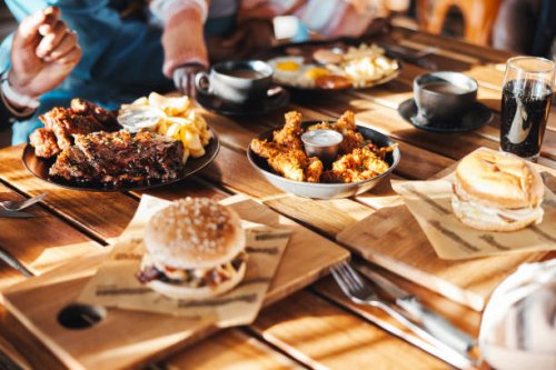 fast food, lunch or dinner on table at restaurant, people eating for nutrition and wellness with time together. catering, hospitality and cuisine with burger, chicken and ribs for protein at diner - junk food stock pictures, 
