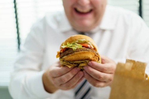fat man eating cheeseburger. - junk food stock pictures, royalty-free photos & images