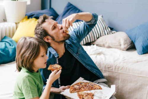 father and son eating pizza at home - junk food stock pictures, royalty-free photos & images