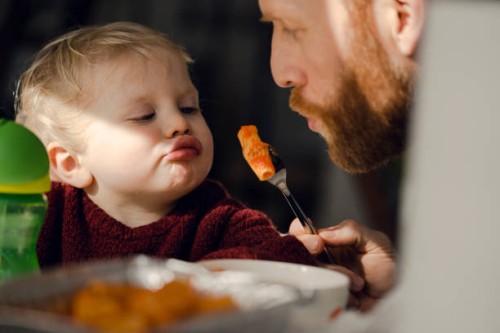 father feeding his little son with tasty pasta - food stockfoto's en -beelden