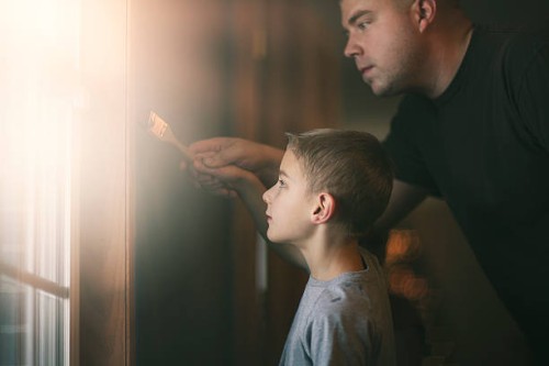 father helping son paint - home decoration stock pictures, royalty-free photos & images