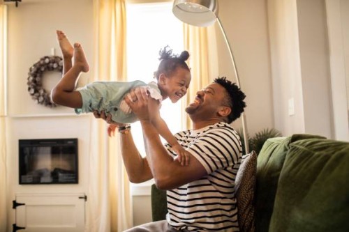 father lifting toddler daughter in the air - home decoration photos et images de collection