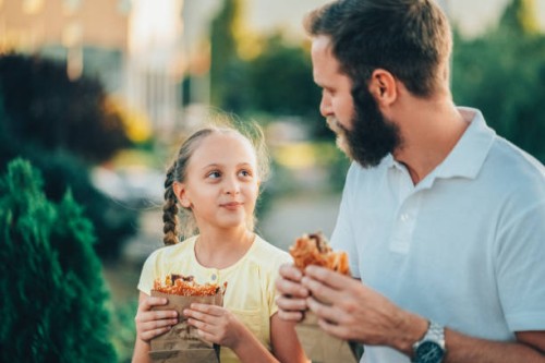 father with daughter eating fast food - junk food stock pictures, royalty-free photos & images