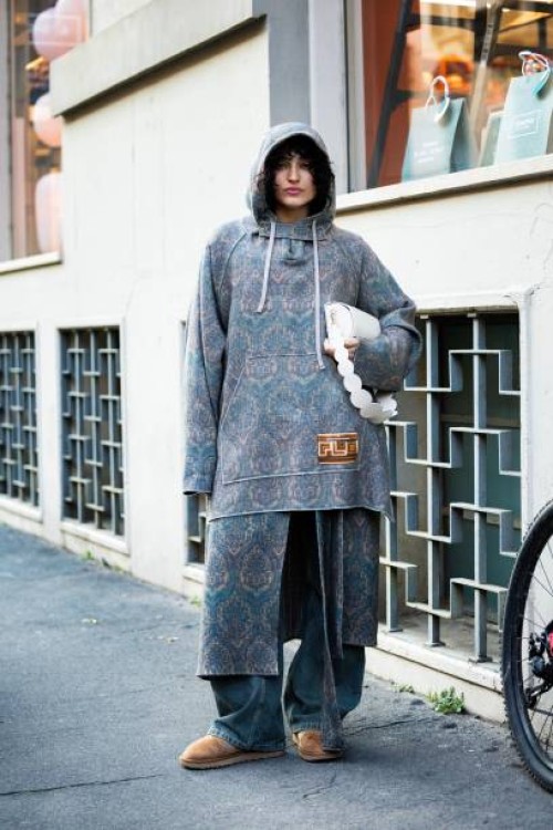 Federica Messaggeri wears beige suede ankle boots, an oversized jacquard lilac and beige hoodie, light greenish denim wide leg trousers and a white...