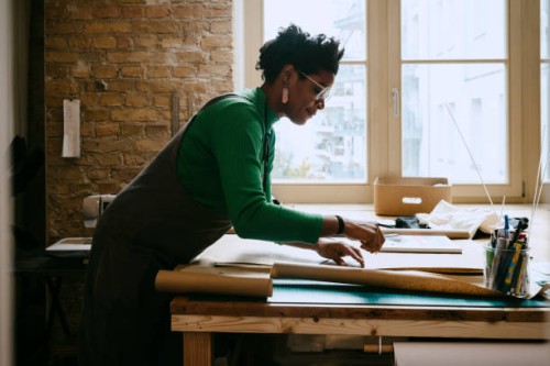 female artist concentrating while doing craft at table in living room - home decoration stock pictures, royalty-free photos & images