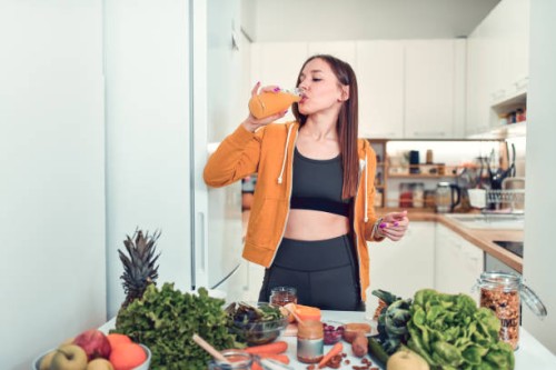 female drinking smoothie to start healthy nutrition while preparing main course at home - food stock pictures, royalty-free photos & images