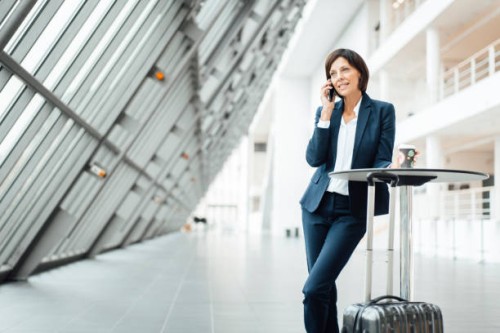 female entrepreneur with coffee cup talking on smart phone in corridor - junk food stock pictures, royalty-free photos & images