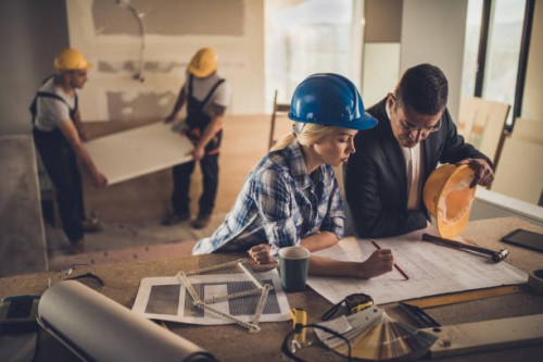 female foreman and male architect analyzing blueprints at construction site. - home decoration stock pictures, royalty-free photos & images