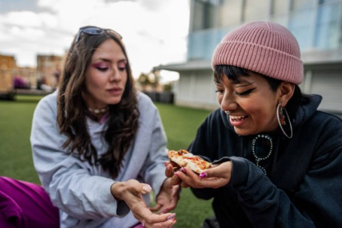 female friends eating pizza at the rooftop - junk food stock pictures, royalty-free photos & images