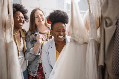 female friends looking at wedding dresses on rack - fashion stock pictures, royalty-free photos & images