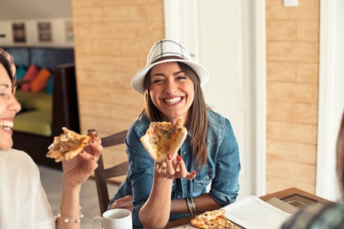female friends sharing a pizza - junk food stock pictures, royalty-free photos & images