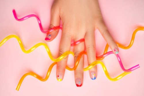 female hand with trendy colorful french manicure is holding three multicolored cocktail straws on pastel pink background. copy space for your design. flat lay style - nails art photos et images de collection
