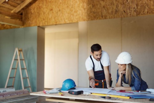 female inspector and manual worker reading housing plans at construction site. - home decoration stockfoto's en -beelden