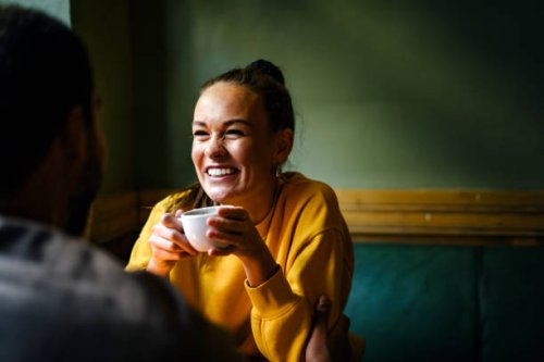 female laughing with friend while drinking coffee - coffee stockfoto's en -beelden