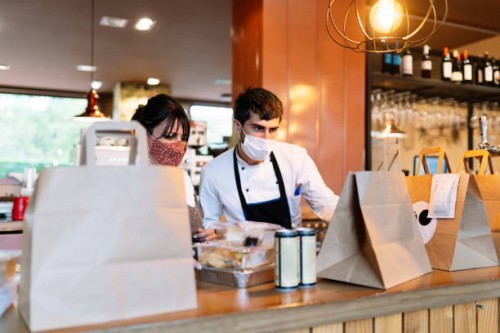 female owner and male chef checking take out food orders on bar counter during pandemic - junk food stock pictures, royalty-free photos & images