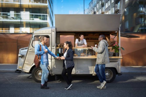 female owner in concession stand while customers having food and drink on street in city - junk food stock pictures, royalty-free photos & images