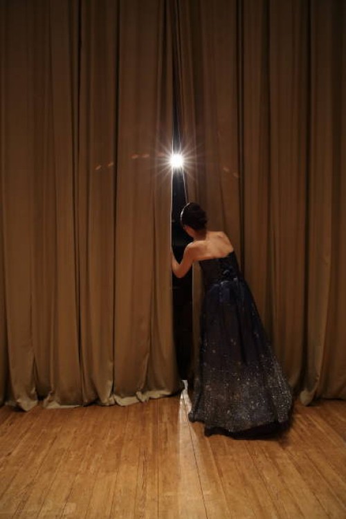 female peeking through curtains of concert hall stage,rear view - concert stock pictures, royalty-free photos & images