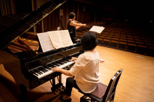 female pianist playing the piano at classical concert with violinist - concert stock pictures, royalty-free photos & images