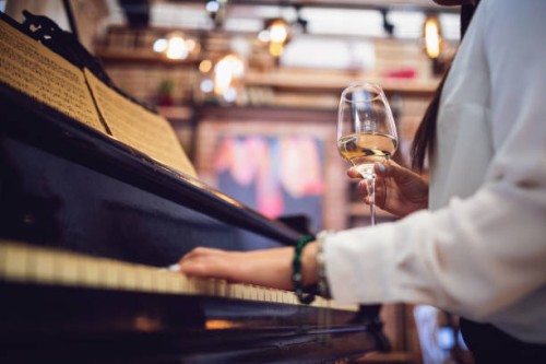 female piano player playing and drinking wine at a restaurant - concert stock pictures, royalty-free photos & images