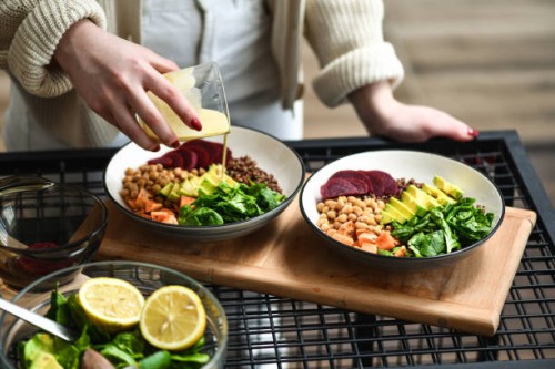 female preparing aesthetically pleasing salad bowls adding dressing on top to tie flavors together - food stock pictures, royalty-free photos & images