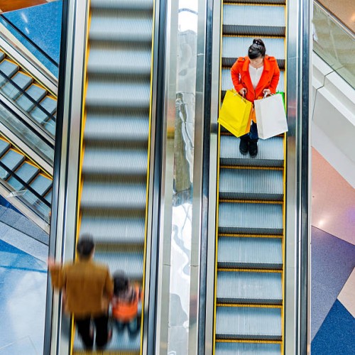 female shopper standing on escalator - fashion stock pictures, royalty-free photos & images
