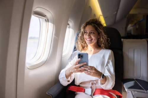 female traveler using her cell phone in an airplane - travel stock pictures, royalty-free photos & images