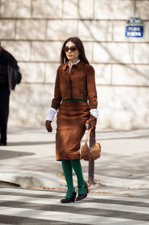 Fer Millan wears green tights, brown skirt, white shirt, brown jacket and brown bag outside the Miu Miu show during Womenswear Spring/Summer 2025 as...