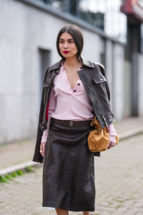 Fernanda Millan wears bright cherry red lipstick, fluffy eyebrows, light pink half unbuttoned long sleeve sweater, shiny black biker leather jacket,...