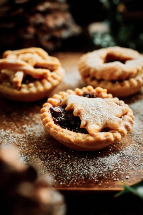 festive scene of 3 home made mince pies dusted with icing sugar on a rustic wooden board with pine cones and holly. - food stock pictures, royalty-free photos & images