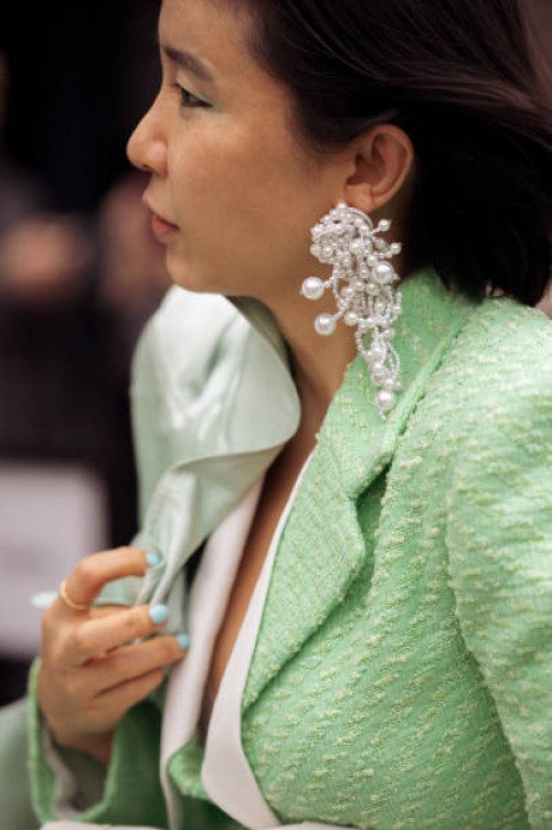 Fiona Kim wearing a lime green jacket, same green color silk coat, white pearl earings outside Fashion east fashion show during London Fashion Week...